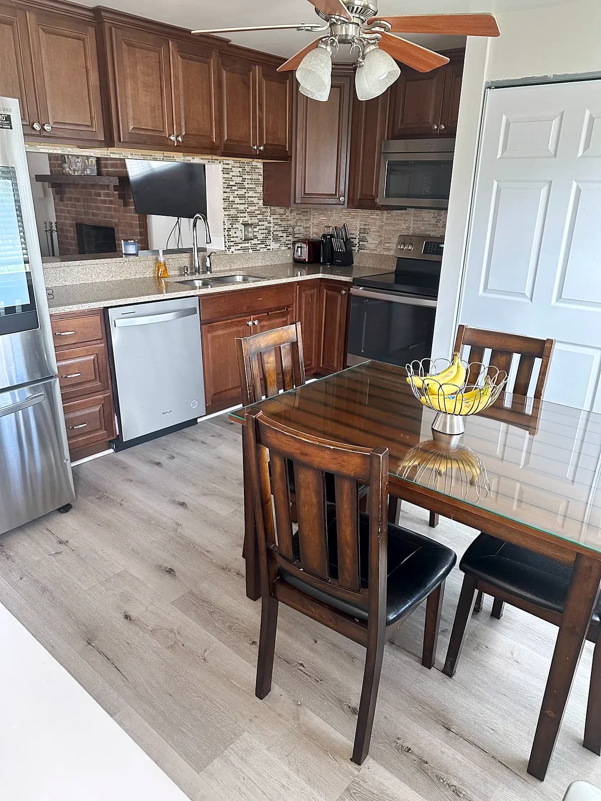 Kitchen with wood cabinets beside a dining table with four chairs