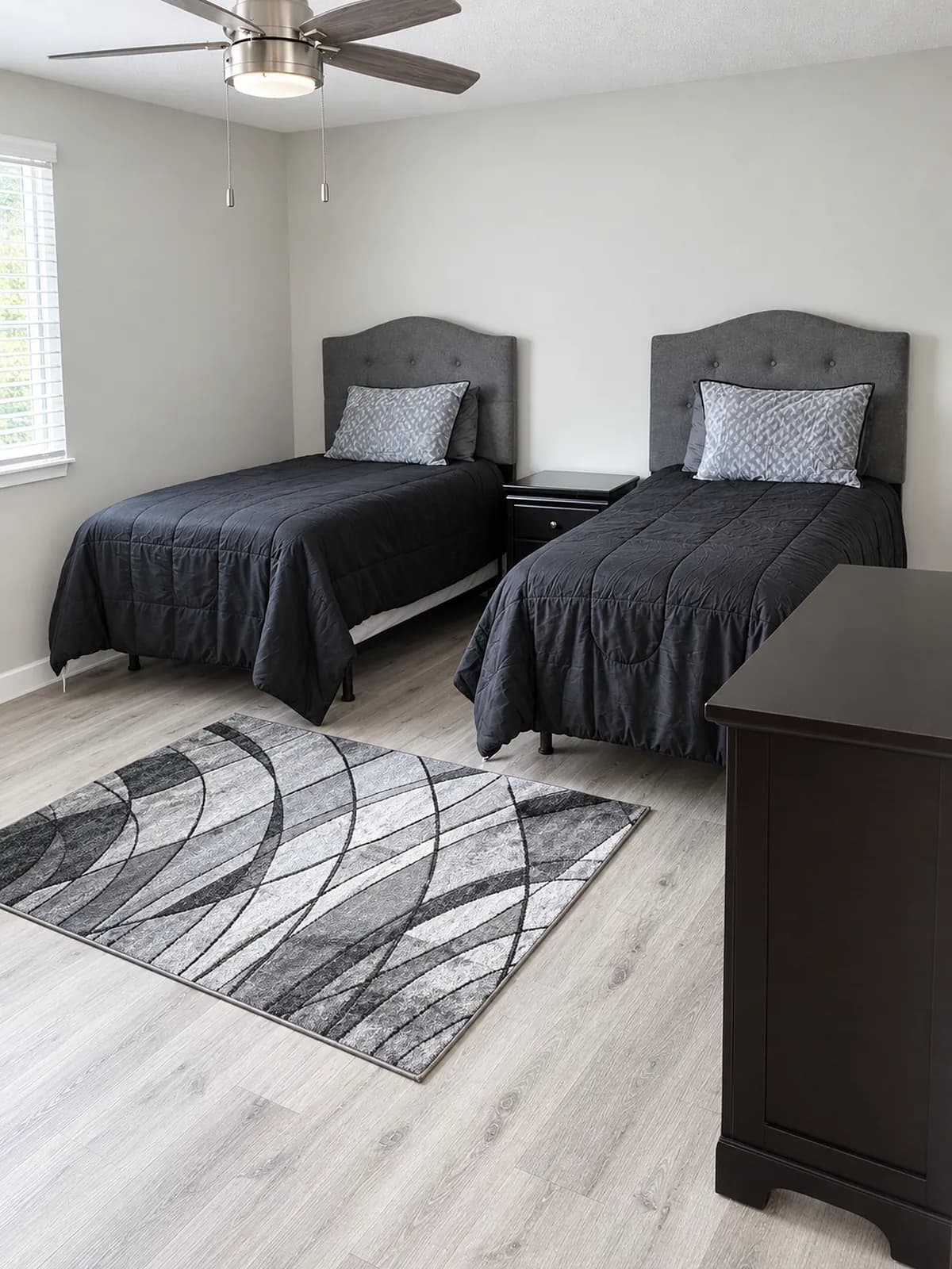 Bedroom with two twin beds, a patterned rug, and a dresser